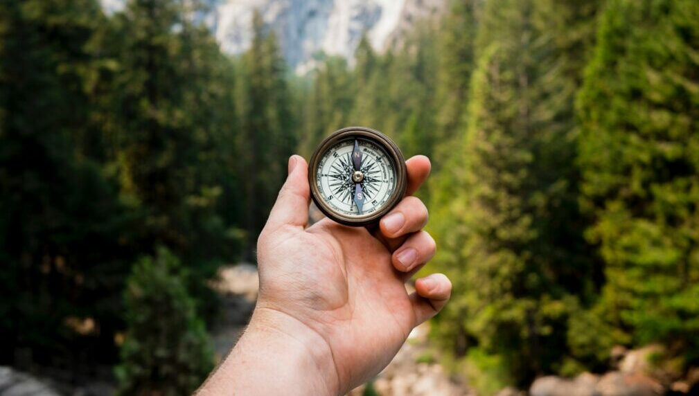 Kompass in der Hand vor einer Landschaftskulisse